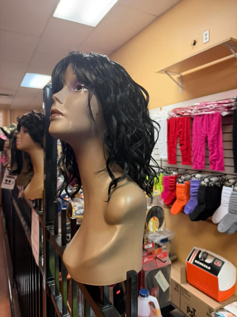 Side view of a black curly wig with bangs on a mannequin at Beyond Image Suites and Supplies in Cincinnati