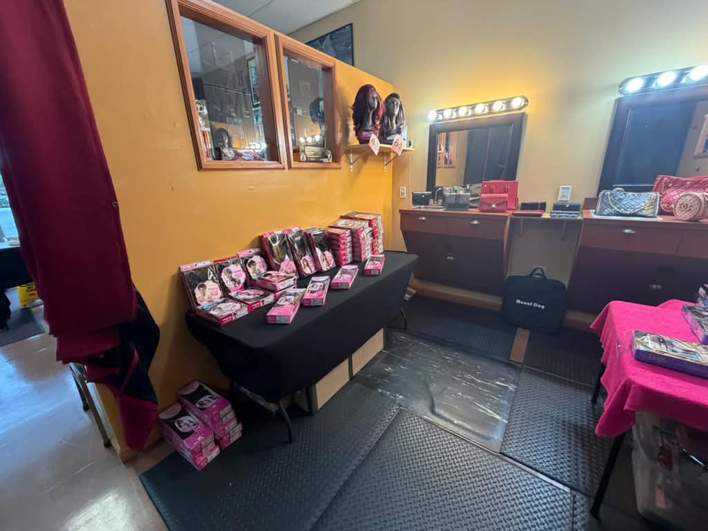 Boxed wigs on a black table beside vanity mirrors and a handbag display at Beyond Image Suites and Supplies