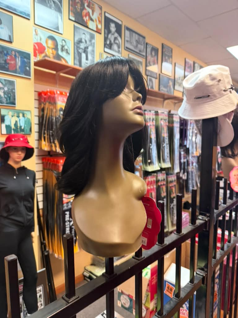 Side view of a dark brown layered feathered wig with bangs on a mannequin at Beyond Image Suites and Supplies