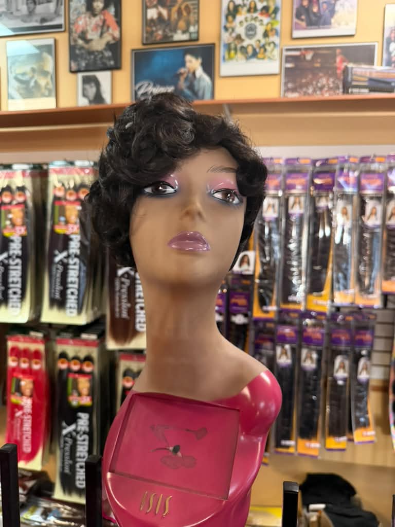 Short dark brown curly pixie wig on a pink Isis mannequin at Beyond Image Suites and Supplies in Cincinnati