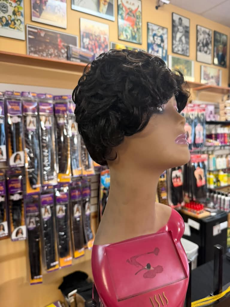 Side view of a short dark brown curly pixie wig on an Isis mannequin at Beyond Image Suites and Supplies