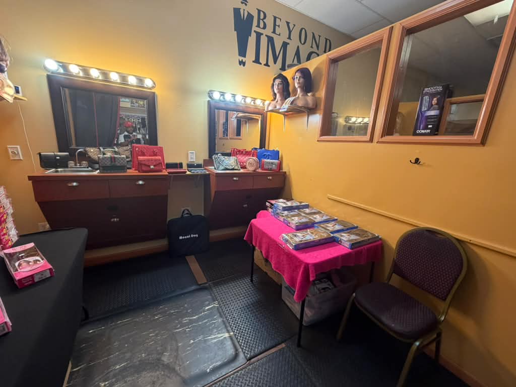Wig try-on room with Beyond Image logo on the wall, lighted mirrors, mannequin heads and boxed wigs